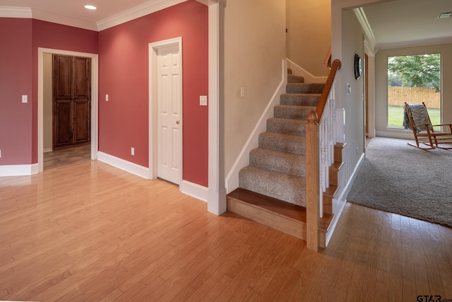 stairway with hardwood / wood-style floors and crown molding