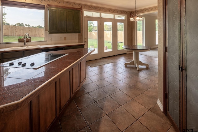 kitchen featuring a healthy amount of sunlight, a chandelier, electric cooktop, hanging light fixtures, and sink