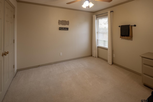 unfurnished bedroom featuring ornamental molding, light colored carpet, ceiling fan, and a closet