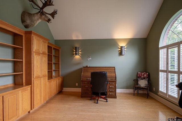 office with light wood-type flooring and lofted ceiling