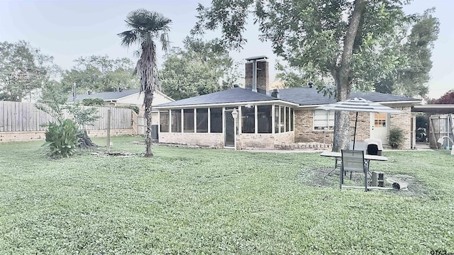 3004 Tower Dr, Tyler, TX 75701 - rear view of property featuring a sunroom, a fenced backyard, brick siding, a chimney, and a shingled roof