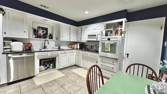 3004 Tower Dr, Tyler, TX 75701 - kitchen with white appliances, decorative backsplash, white cabinets, dark countertops, and recessed lighting