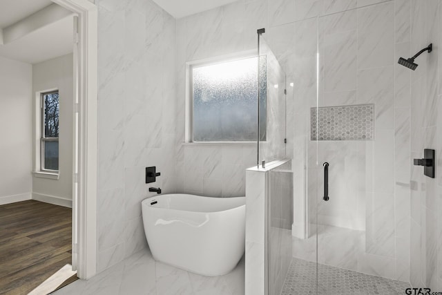 bathroom featuring a soaking tub, a tile shower, tile walls, and wood finished floors