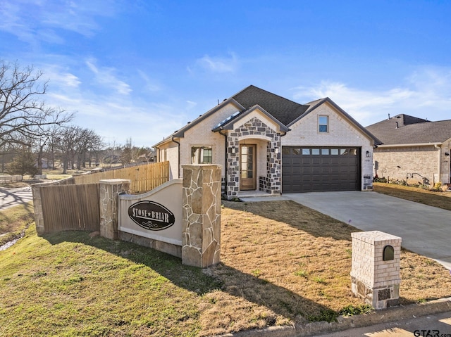 french country home with a garage, brick siding, fence, concrete driveway, and a front lawn