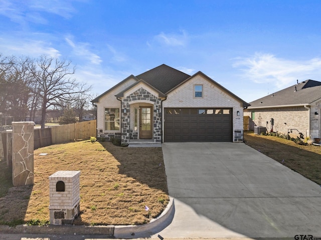 french provincial home featuring an attached garage, central air condition unit, brick siding, fence, and driveway