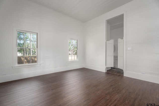 unfurnished room featuring baseboards and dark wood-style flooring