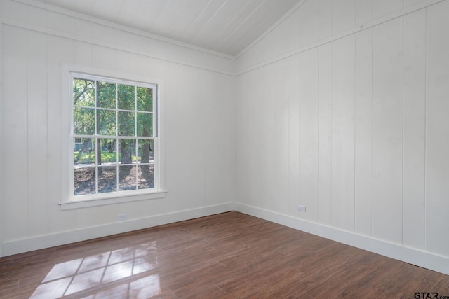 empty room featuring vaulted ceiling, dark wood-type flooring, and baseboards