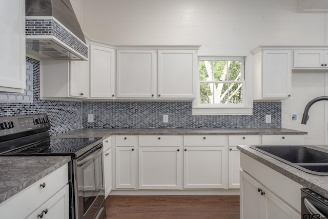 kitchen featuring tasteful backsplash, stainless steel dishwasher, a sink, range with electric cooktop, and wall chimney exhaust hood