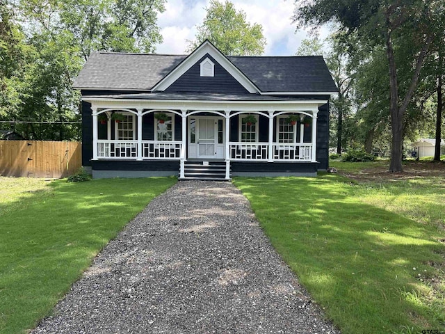 view of front of property featuring a shingled roof, covered porch, fence, and a front lawn