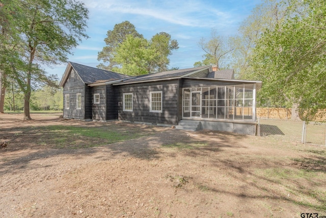 back of property with a sunroom, a chimney, and fence