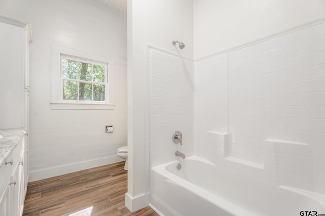 bathroom with baseboards, toilet, vanity, wood finished floors, and shower / bathtub combination