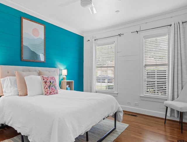 bedroom with wood-type flooring, ceiling fan, and crown molding