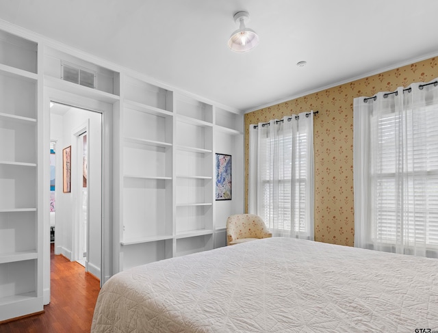 bedroom featuring multiple windows, hardwood / wood-style flooring, and crown molding