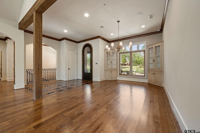 5581 Nancy Cir, Chandler, TX 75758 - spare room with arched walkways, a chandelier, wood finished floors, crown molding, and baseboards