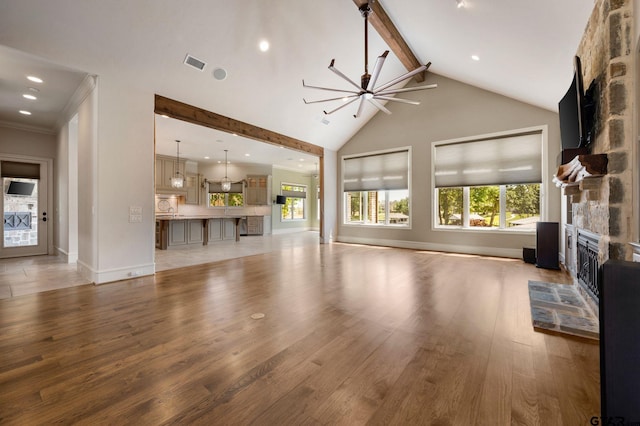 5581 Nancy Cir, Chandler, TX 75758 - unfurnished living room featuring a stone fireplace, beam ceiling, plenty of natural light, light wood-style floors, and high vaulted ceiling