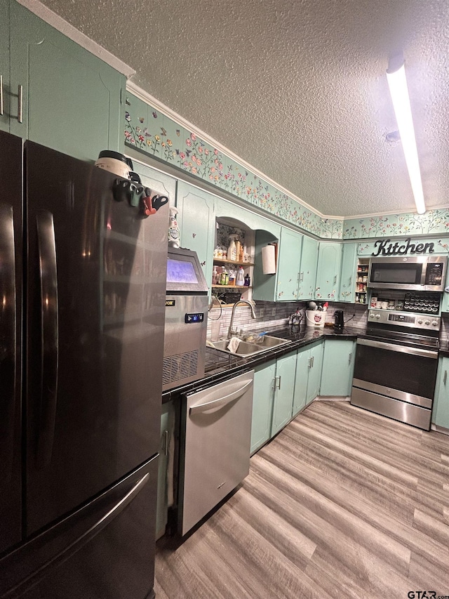 kitchen with sink, crown molding, a textured ceiling, appliances with stainless steel finishes, and light hardwood / wood-style floors