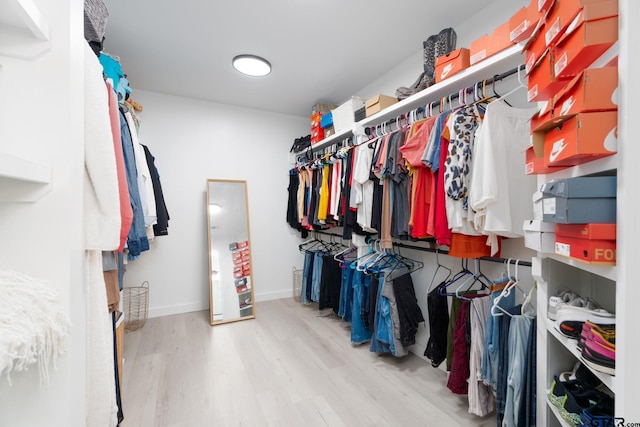 walk in closet with light hardwood / wood-style flooring