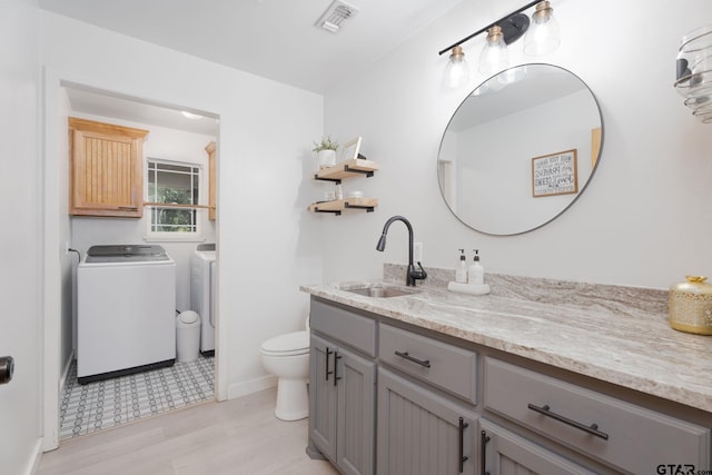 bathroom featuring washing machine and clothes dryer, vanity, and toilet