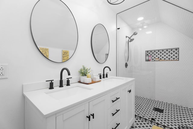 bathroom featuring a tile shower, vanity, and vaulted ceiling