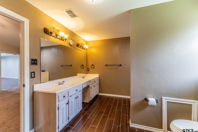 1853 Woodbridge Dr, Sulphur Springs, TX 75482 - full bath with baseboards, double vanity, wood finished floors, toilet, and a textured wall