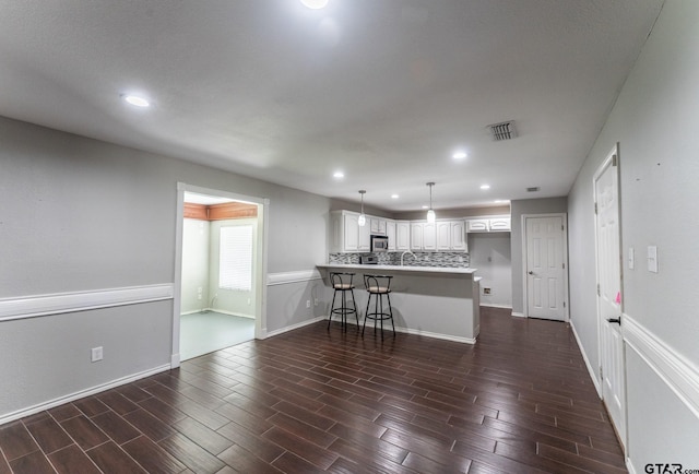 1853 Woodbridge Dr, Sulphur Springs, TX 75482 - kitchen featuring a peninsula, stainless steel microwave, recessed lighting, white cabinets, and a kitchen bar
