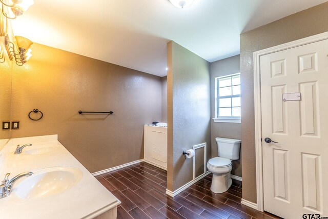 1853 Woodbridge Dr, Sulphur Springs, TX 75482 - bathroom with toilet, wood finish floors, baseboards, double vanity, and a textured wall