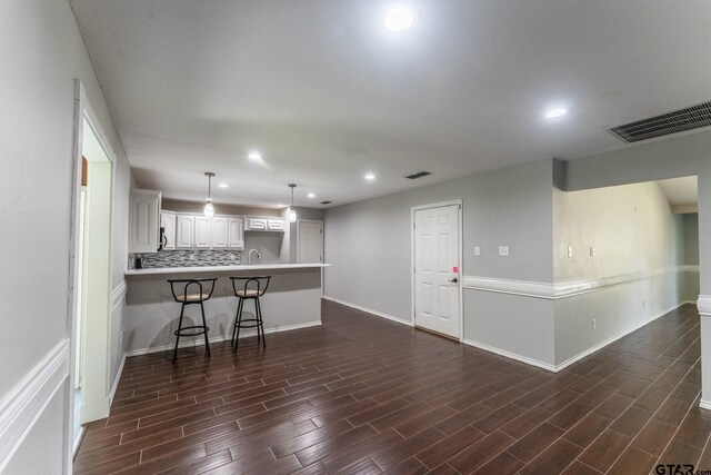 1853 Woodbridge Dr, Sulphur Springs, TX 75482 - kitchen featuring a peninsula, recessed lighting, white cabinets, a breakfast bar, and dark wood-style floors