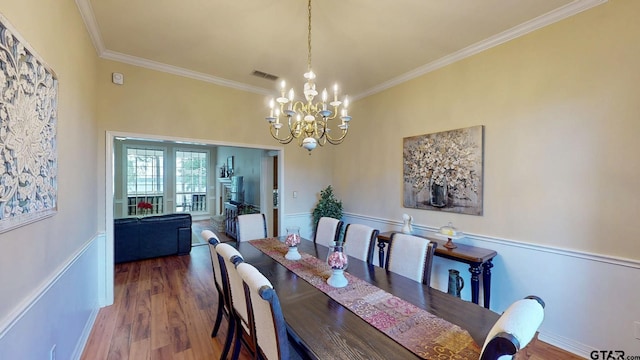 dining room featuring a chandelier, wood finished floors, visible vents, and crown molding