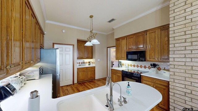kitchen with backsplash, pendant lighting, brown cabinetry, light countertops, and black appliances