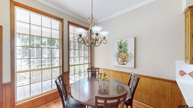 dining space with a chandelier, light wood-style floors, ornamental molding, and wainscoting