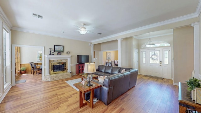 living room featuring a wealth of natural light, crown molding, light wood-style floors, and visible vents