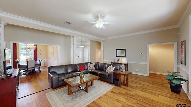 living room with ceiling fan with notable chandelier, light wood-style flooring, ornamental molding, visible vents, and decorative columns