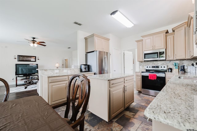 224 Cass Cir, Flint, TX 75762 - kitchen with appliances with stainless steel finishes, tasteful backsplash, a peninsula, and cream cabinetry