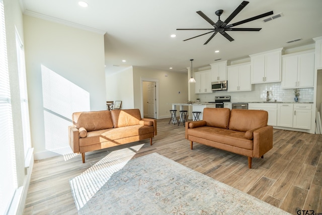 living room featuring sink, light hardwood / wood-style flooring, ornamental molding, and ceiling fan