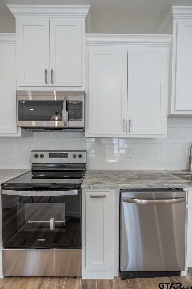 kitchen featuring stainless steel appliances, white cabinetry, and tasteful backsplash