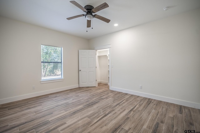 empty room with ceiling fan and light hardwood / wood-style flooring