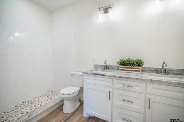 bathroom featuring hardwood / wood-style flooring, vanity, a tile shower, and toilet