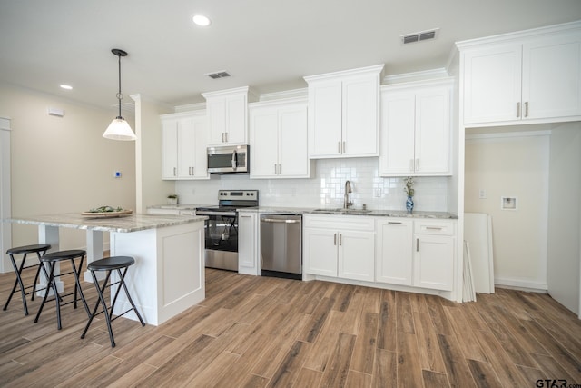 kitchen featuring pendant lighting, appliances with stainless steel finishes, sink, and white cabinets