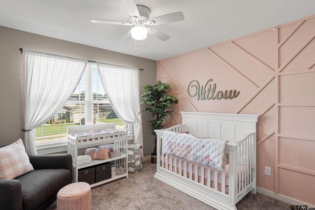 carpeted bedroom with ceiling fan and a crib