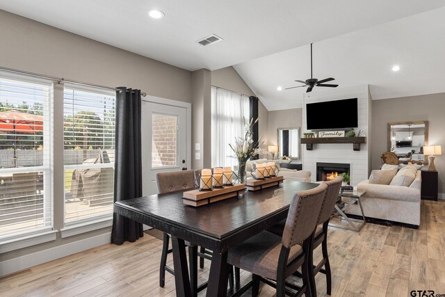 dining area with ceiling fan, a fireplace, light hardwood / wood-style floors, and lofted ceiling