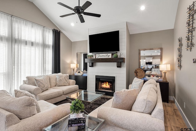 living room featuring a fireplace, hardwood / wood-style floors, vaulted ceiling, and a healthy amount of sunlight