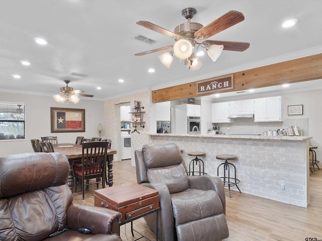 living room with crown molding, ceiling fan, and light hardwood / wood-style floors