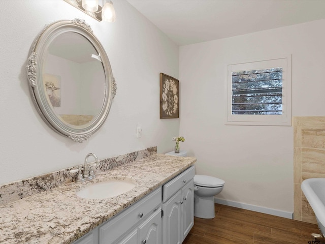 bathroom featuring vanity, hardwood / wood-style flooring, toilet, and a bathtub