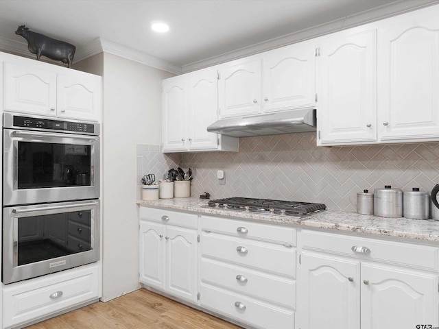 kitchen with appliances with stainless steel finishes, tasteful backsplash, crown molding, light hardwood / wood-style flooring, and white cabinetry