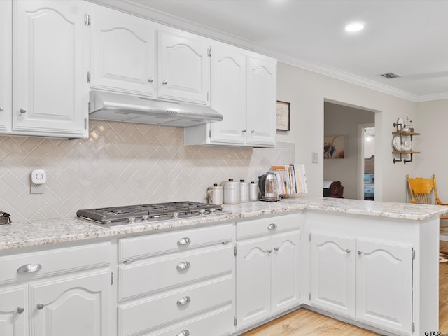 kitchen featuring white cabinets, tasteful backsplash, ornamental molding, and light hardwood / wood-style floors