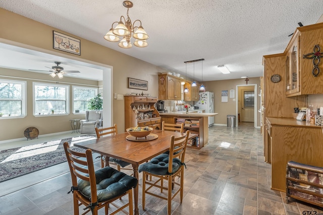 dining space with ceiling fan with notable chandelier and a textured ceiling