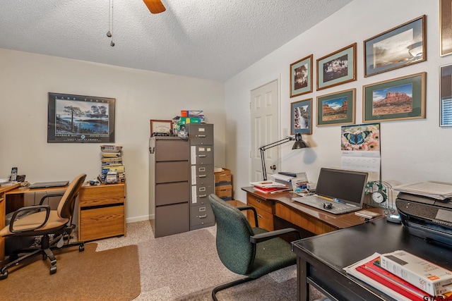 home office featuring light carpet, ceiling fan, and a textured ceiling