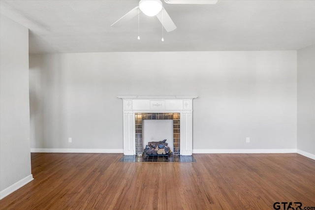 unfurnished living room with a tiled fireplace, dark hardwood / wood-style flooring, and ceiling fan