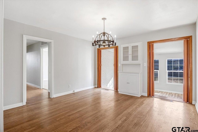 unfurnished dining area with hardwood / wood-style floors and a chandelier