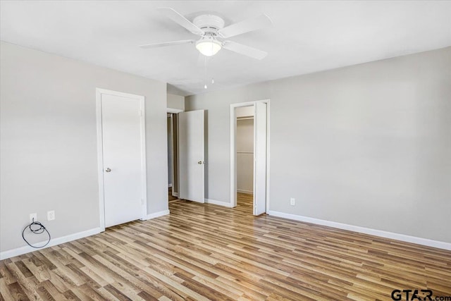 unfurnished bedroom with a walk in closet, light hardwood / wood-style floors, a closet, and ceiling fan